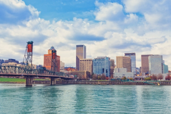 Portland city skyline viewed from the river with bridges and high-rise buildings under a blue sky.