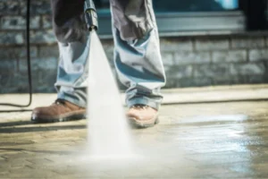 A worker using a high-pressure washer on a surface, demonstrating commercial cleaning services.