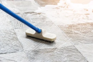 A brush scrubbing tile flooring with cleaning solution, showcasing tile and grout cleaning services.