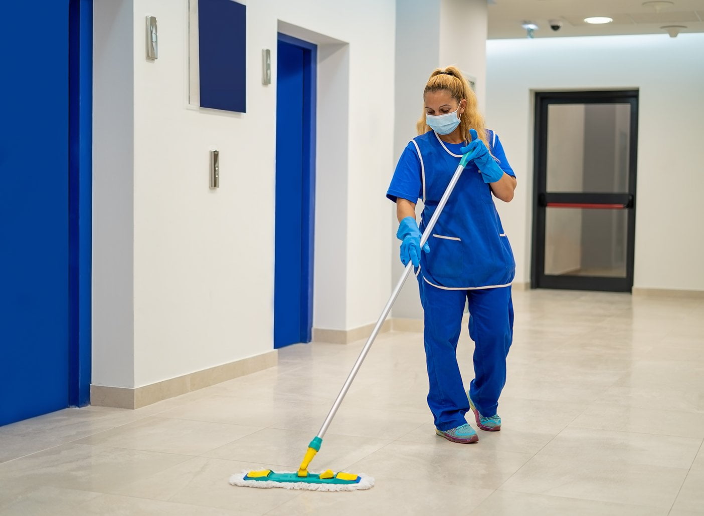 Professional cleaner mopping a hallway in a commercial building.