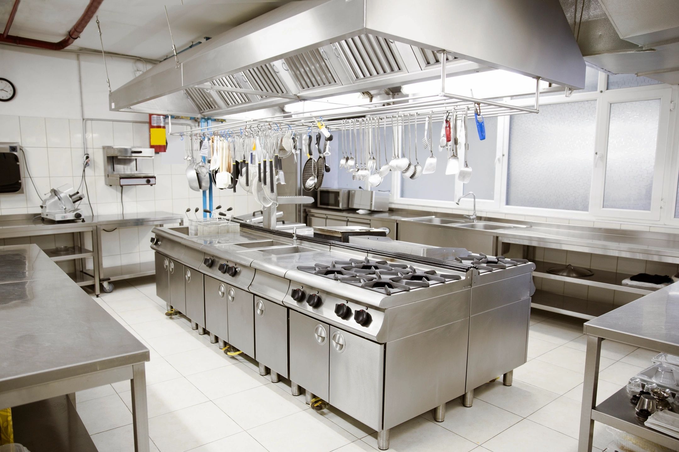 A clean and organized hotel kitchen with stainless steel countertops and cooking equipment, highlighting the effectiveness of our hotel cleaning services, especially in kitchen and food prep areas.