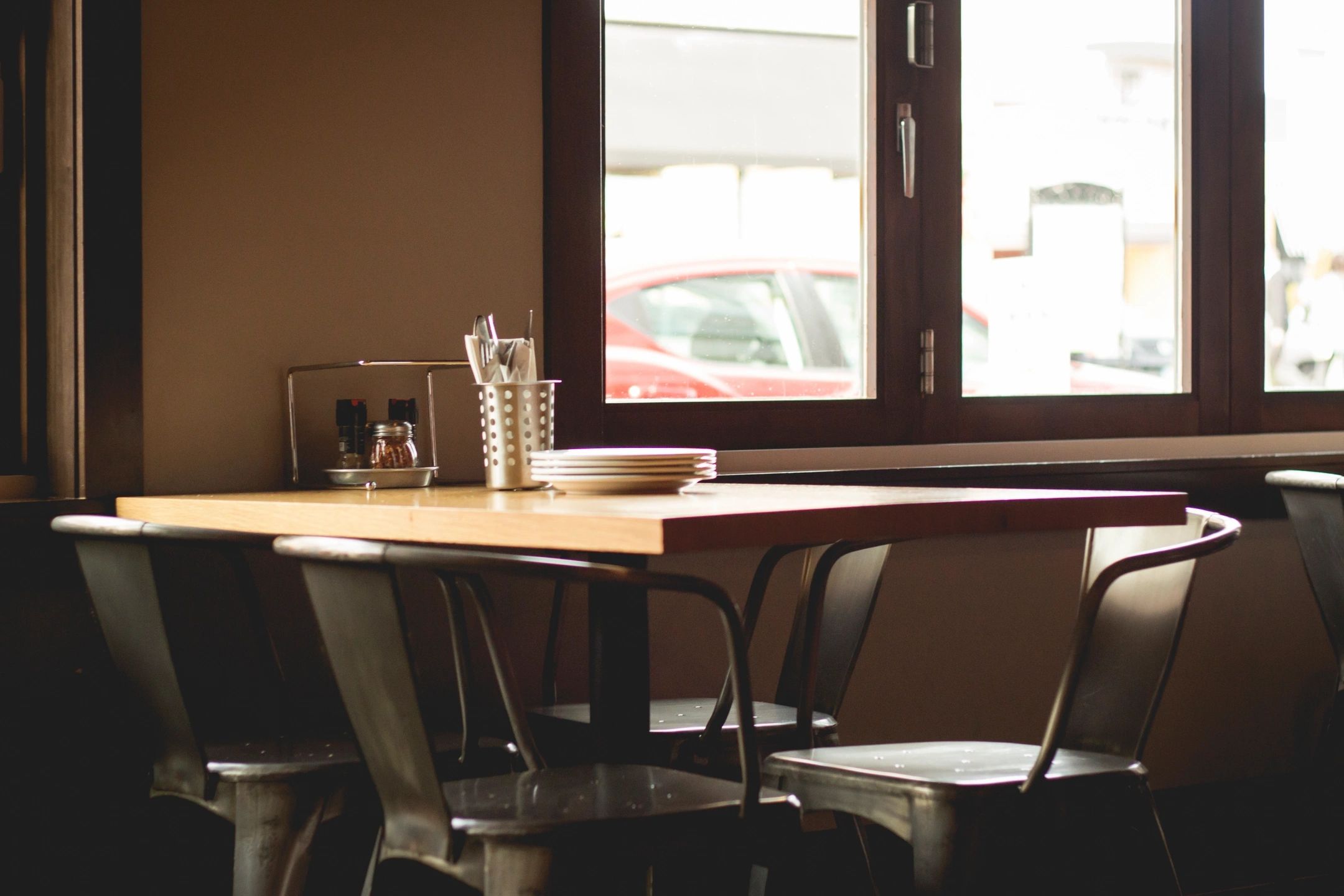 A cozy restaurant table with simple settings, located by a large window, allowing natural light to fill the space.