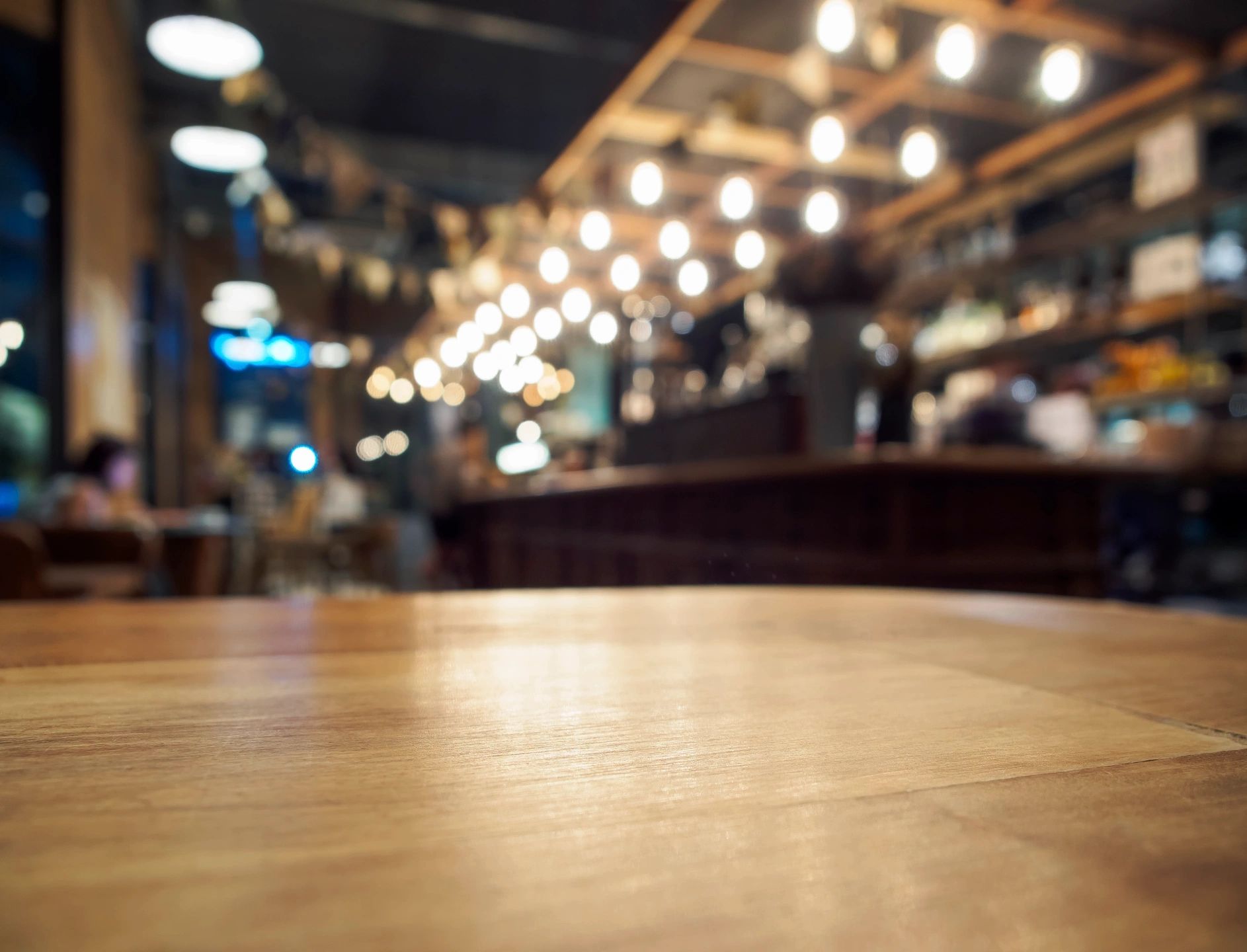 Warmly lit restaurant dining area with a clean wooden table in focus, showcasing professional restaurant cleaning services.