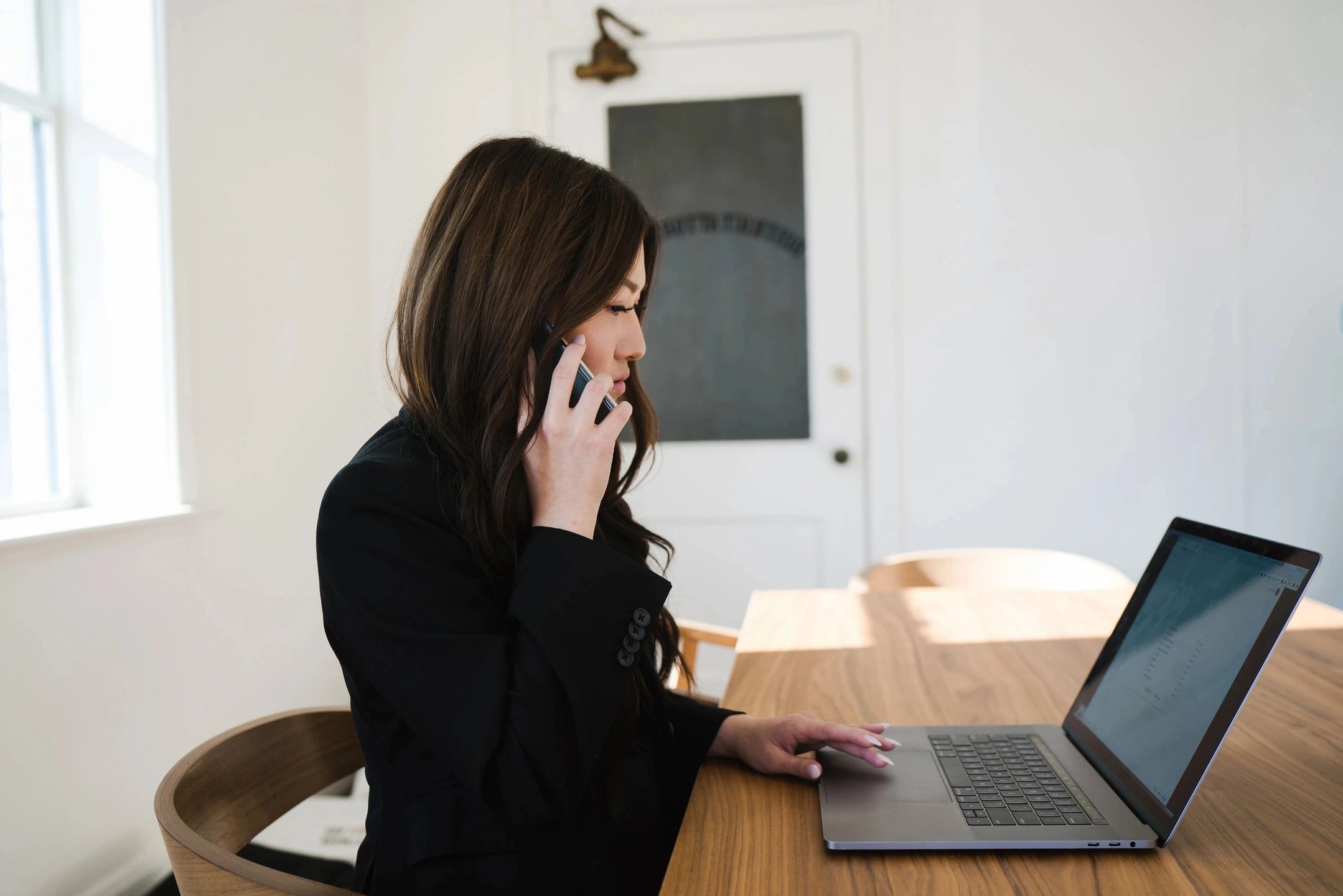 Hotel employee in a back office on a phone and laptop, highlighting the importance of hotel cleaning services in maintaining clean and organized workspaces.