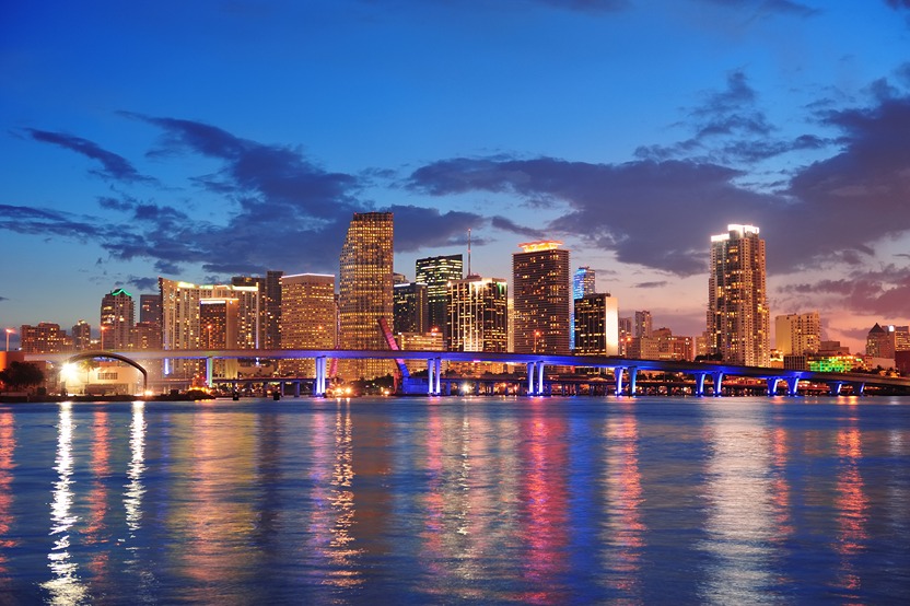 Miami skyline at sunset with vibrant city lights reflecting off the water, representing commercial cleaning services in Miami, FL.