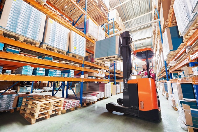 Forklift operating in a warehouse with stacked pallets and shelves, emphasizing the importance of industrial cleaning services for warehouses and distribution centers.