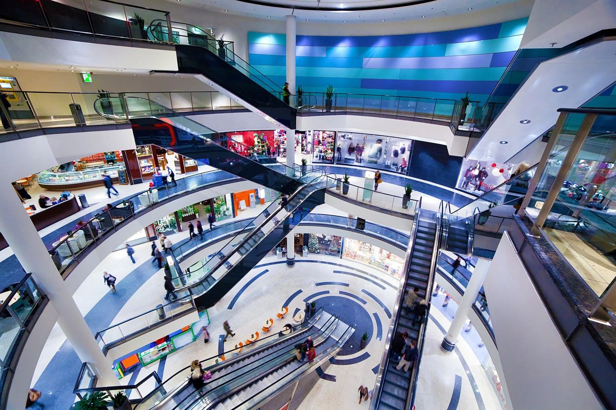 A clean and spacious shopping mall with polished floors and well-maintained escalators, showcasing professional shopping mall cleaning services.