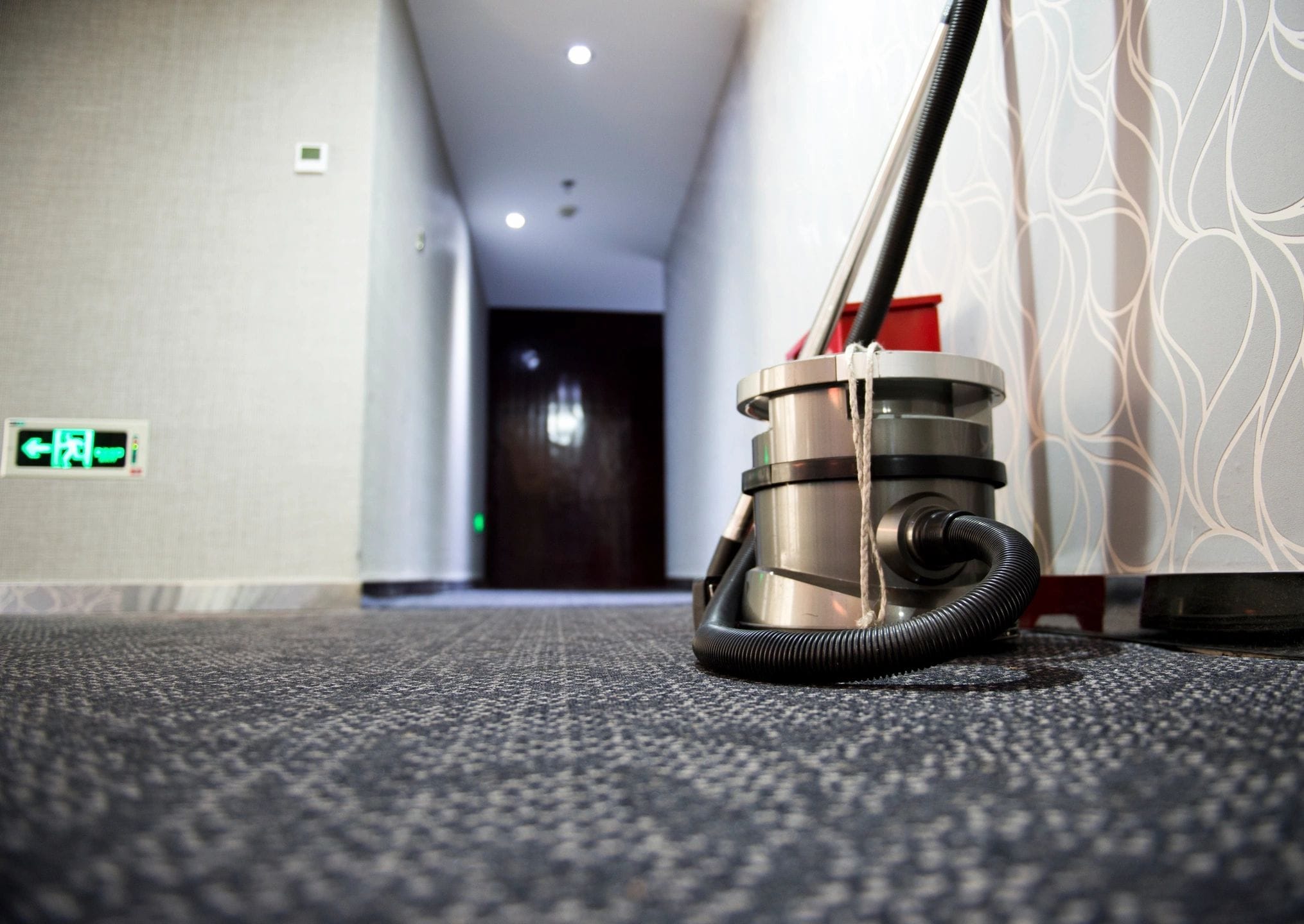 Commercial vacuum cleaner in a carpeted hallway, ready for floor cleaning services.