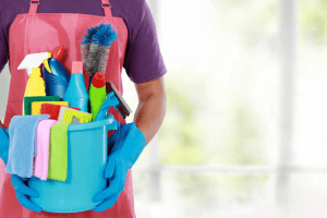 Person holding a bucket with various cleaning supplies for office cleaning services.