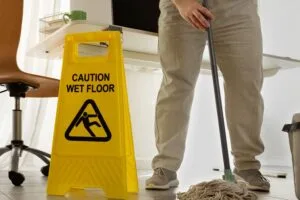 Janitorial services in Phoenix AZ with a caution wet floor sign and a worker mopping in an office space.