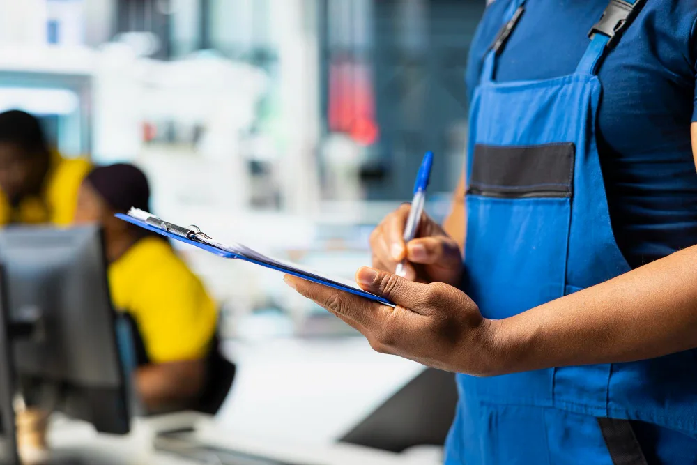 Worker reviewing a cleaning checklist on a clipboard inside a professional facility for A&M Janitorial Services.