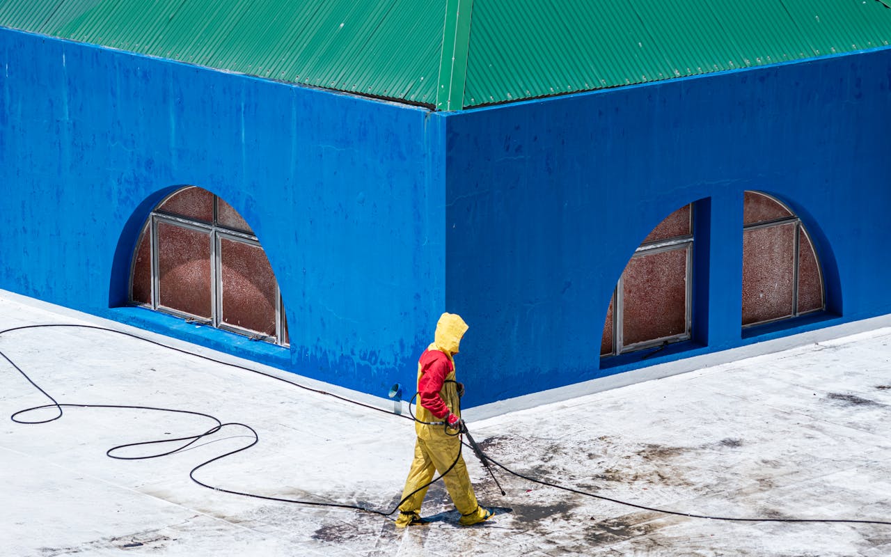 Professional pressure washing technician cleaning a commercial building exterior and concrete surface in Portland, OR