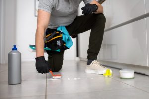 Professional cleaner scrubbing tile grout with a small brush during commercial tile cleaning.