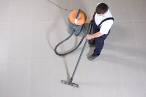 Commercial floor cleaning services using a professional vacuum on tiled floors.